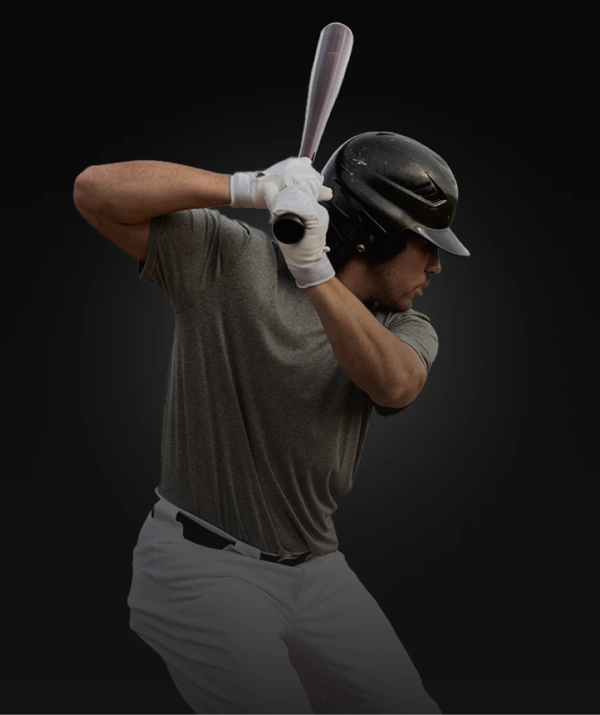 A baseball player wearing a helmet and gloves is poised to swing a bat, set against a dark background.
